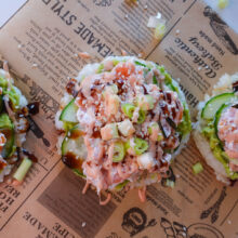 Knusprige Sushi-Waffeln aus Reis mit Avocado, Räucherlachs und Spicy Mayo auf Backpapier angerichtet