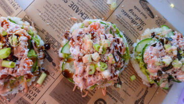 Knusprige Sushi-Waffeln aus Reis mit Avocado, Räucherlachs und Spicy Mayo auf Backpapier angerichtet