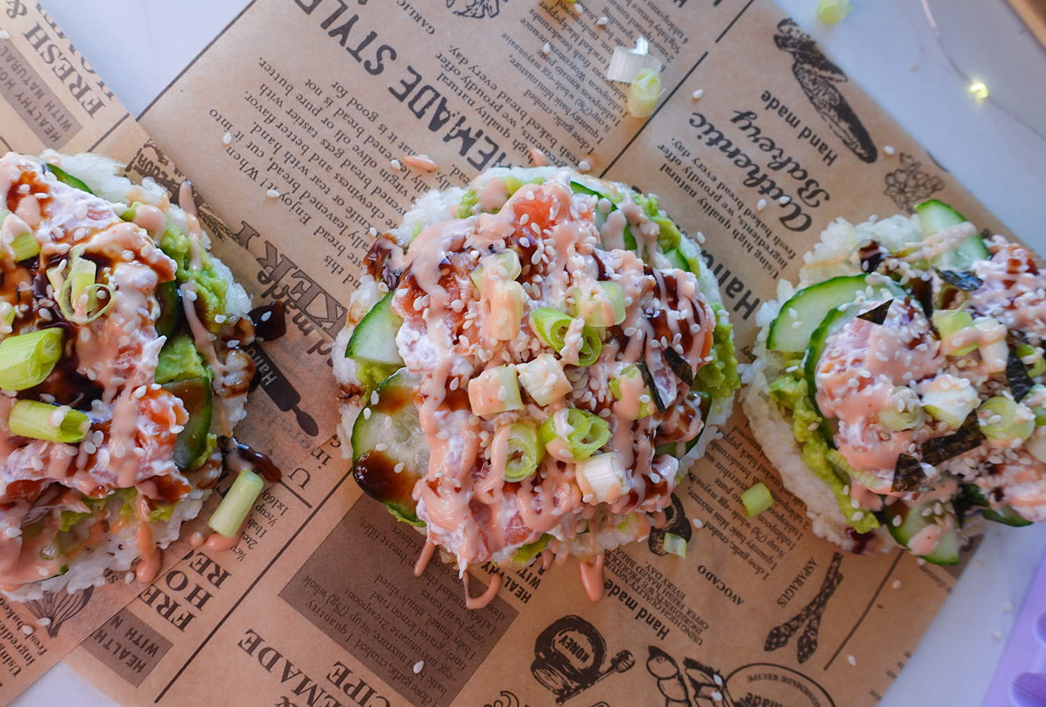 Knusprige Sushi-Waffeln aus Reis mit Avocado, Räucherlachs und Spicy Mayo auf Backpapier angerichtet